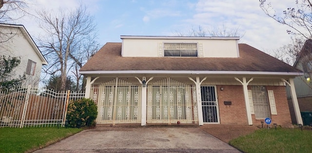 view of front of house with brick siding, fence, and roof with shingles