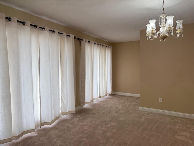 unfurnished room featuring carpet floors, a chandelier, and baseboards