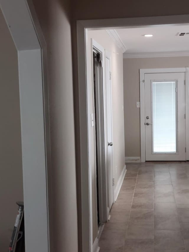 hallway with baseboards, ornamental molding, visible vents, and light tile patterned floors