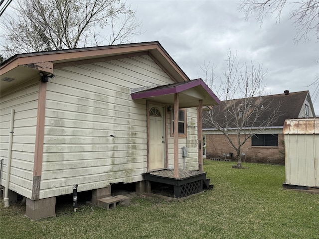 back of property featuring a storage shed, an outbuilding, and a yard