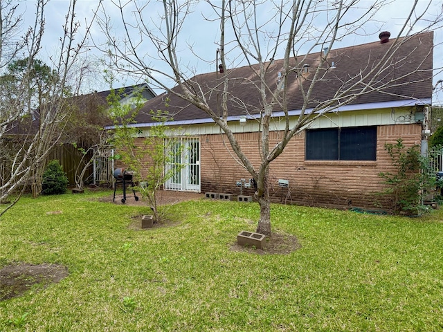 back of house featuring a patio, a lawn, and brick siding