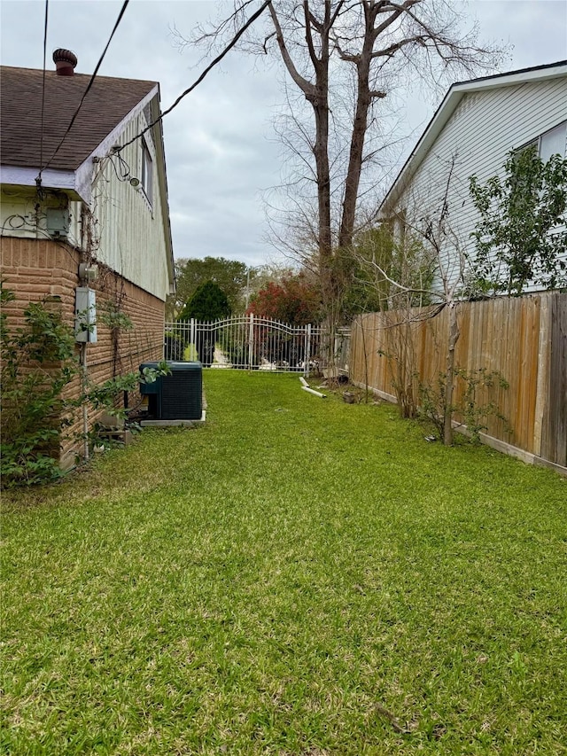 view of yard with central AC and a fenced backyard