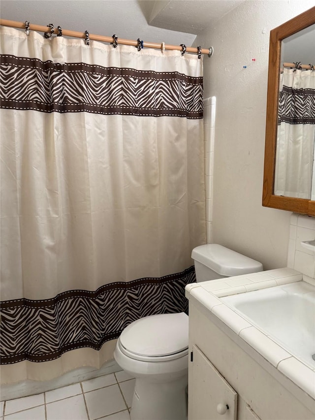 full bathroom featuring a textured wall, vanity, toilet, and tile patterned floors