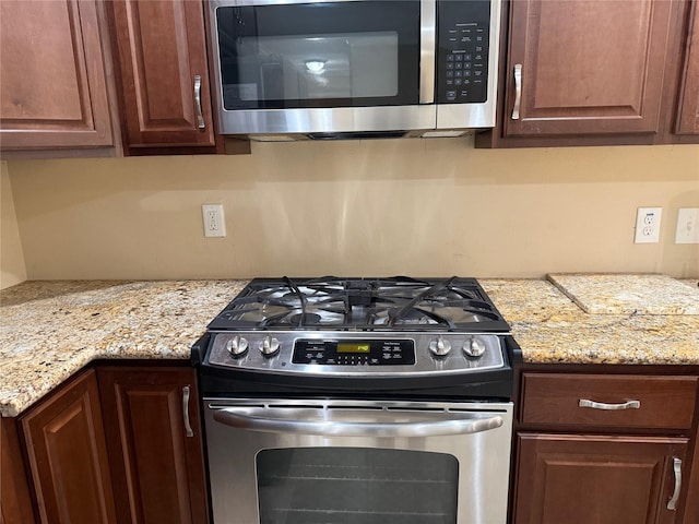 kitchen with appliances with stainless steel finishes and light stone counters