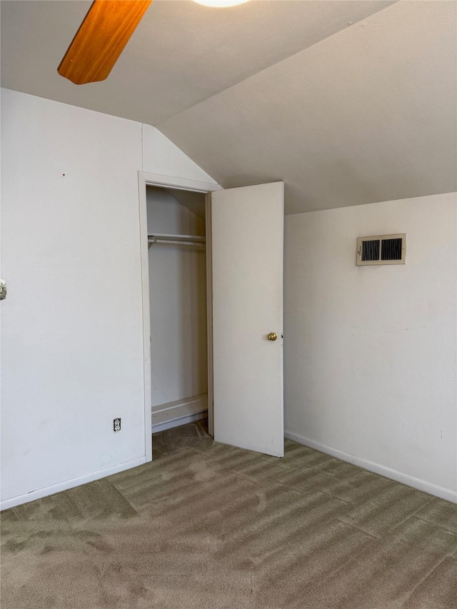 unfurnished bedroom featuring carpet floors, lofted ceiling, a closet, and visible vents