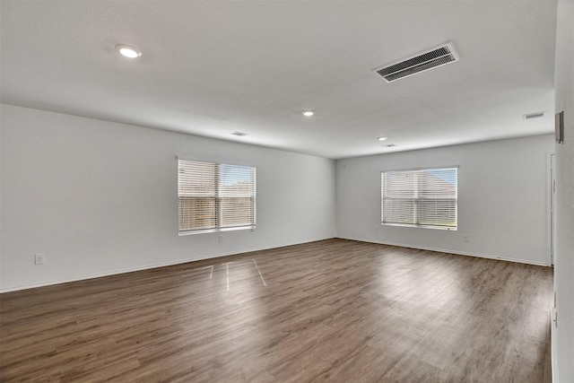 unfurnished room with a healthy amount of sunlight, visible vents, and wood finished floors