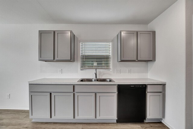 kitchen featuring gray cabinets, light countertops, a sink, light wood-type flooring, and dishwasher