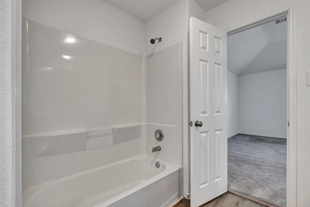 full bathroom with visible vents, vaulted ceiling, wood finished floors, and washtub / shower combination