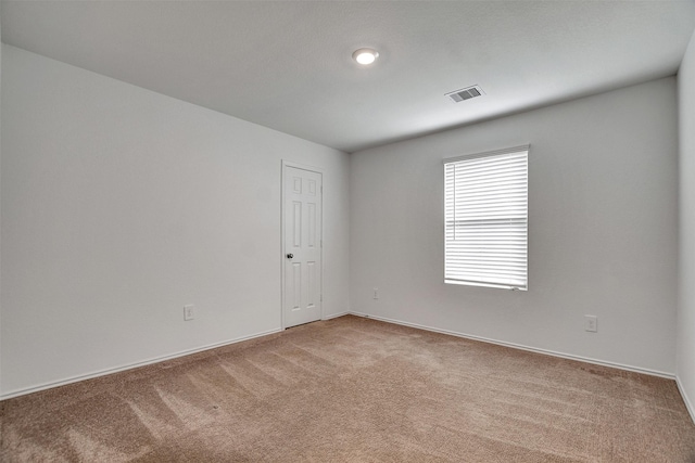 empty room featuring carpet flooring, visible vents, and baseboards