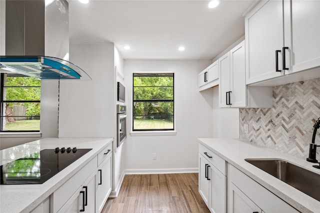 kitchen featuring island exhaust hood, black electric stovetop, stainless steel oven, a sink, and built in microwave