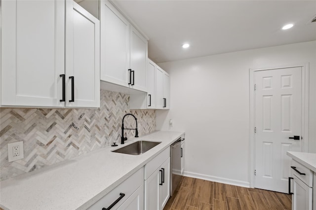 kitchen featuring dishwasher, wood finished floors, a sink, and white cabinetry