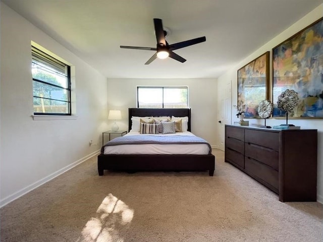 bedroom featuring multiple windows, baseboards, a ceiling fan, and light colored carpet