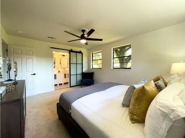 carpeted bedroom featuring ceiling fan, a barn door, and visible vents