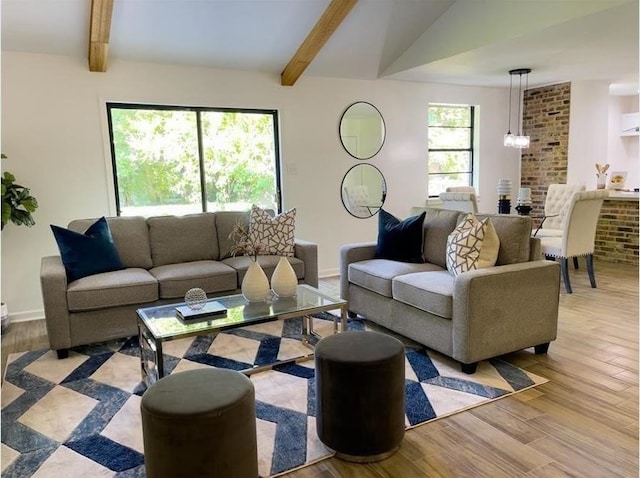 living area featuring a notable chandelier, lofted ceiling with beams, baseboards, and wood finished floors