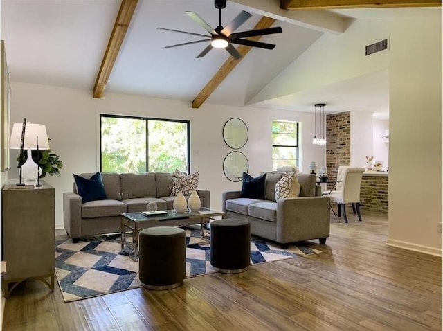 living room featuring ceiling fan, wood finished floors, visible vents, baseboards, and beamed ceiling