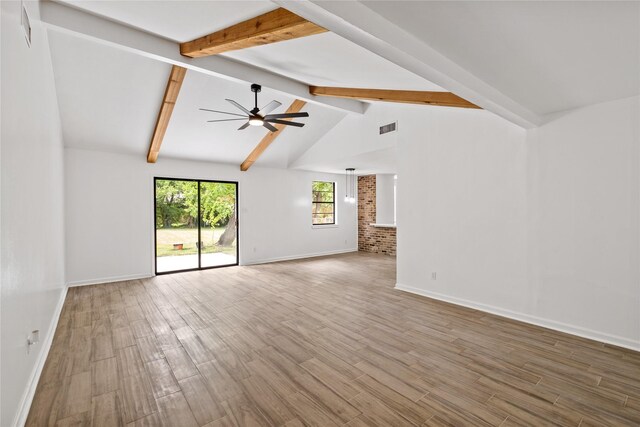 unfurnished living room with visible vents, lofted ceiling with beams, a ceiling fan, wood finished floors, and baseboards