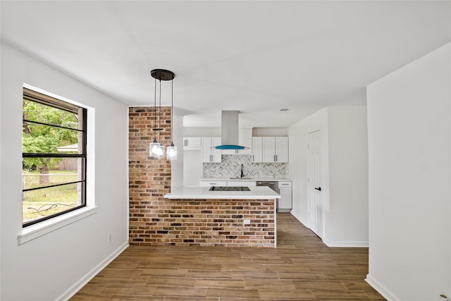 kitchen with light countertops, backsplash, white cabinetry, a sink, and island range hood