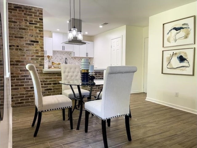 dining room with dark wood-type flooring, recessed lighting, brick wall, and baseboards