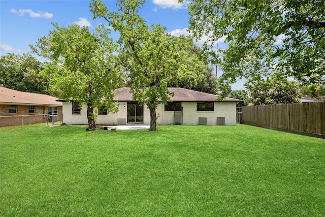 back of house featuring brick siding, a fenced backyard, a lawn, and a patio