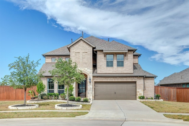 french provincial home featuring a shingled roof, fence, and brick siding