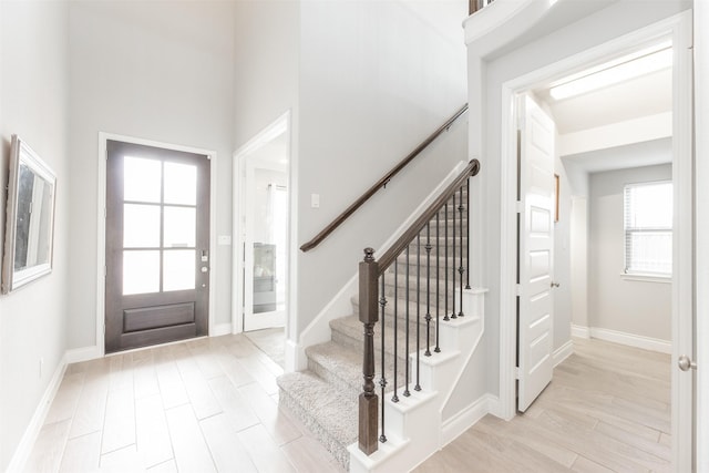 entryway featuring baseboards, stairway, and light wood-style floors