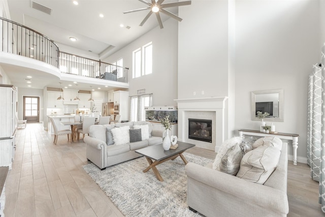 living room featuring visible vents, baseboards, a tile fireplace, light wood-style flooring, and recessed lighting