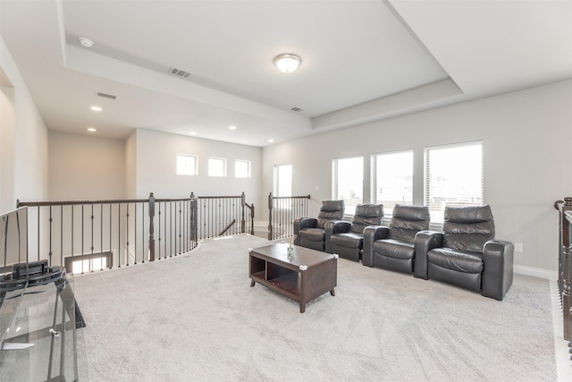 carpeted living area with a healthy amount of sunlight, visible vents, baseboards, and a raised ceiling