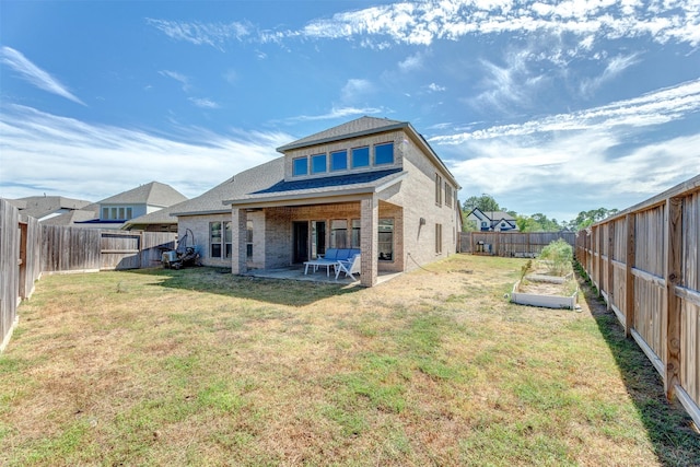 back of house with a patio, brick siding, a lawn, and a fenced backyard