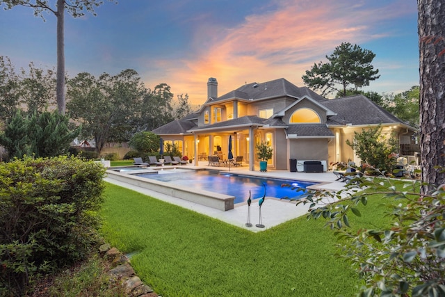 back of house featuring a patio, an outdoor hangout area, a lawn, an outdoor pool, and a chimney