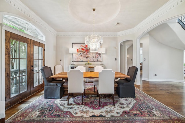 dining room featuring arched walkways, a notable chandelier, wood finished floors, baseboards, and french doors