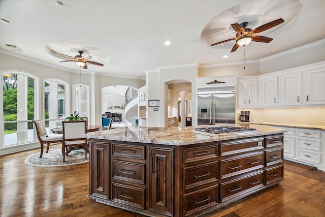 kitchen featuring arched walkways, dark wood-style flooring, visible vents, appliances with stainless steel finishes, and white cabinetry