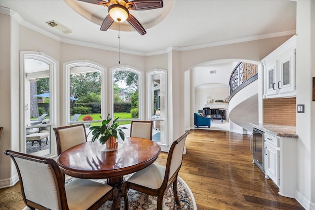 dining space with a tray ceiling, crown molding, visible vents, and dark wood-style flooring