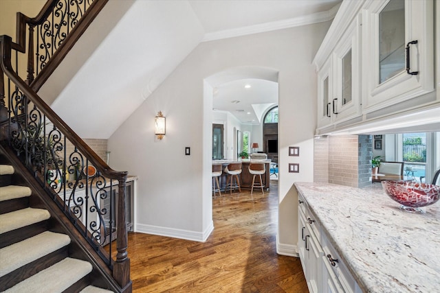 interior space with arched walkways, recessed lighting, wood finished floors, baseboards, and crown molding