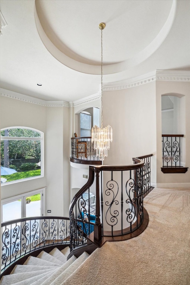 interior space with a chandelier, a towering ceiling, ornamental molding, carpet, and a raised ceiling