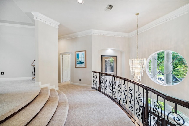 hallway with a notable chandelier, visible vents, baseboards, carpet, and crown molding