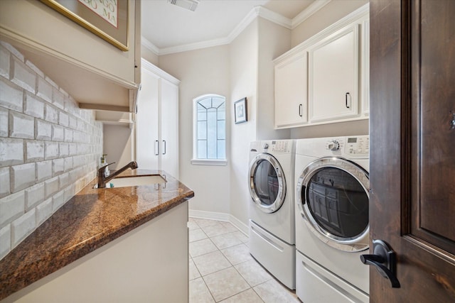 washroom with ornamental molding, washing machine and dryer, cabinet space, and a sink