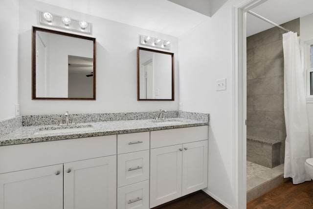 full bath featuring tiled shower, wood finished floors, and a sink