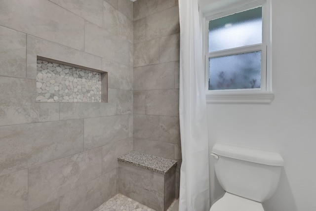 bathroom featuring toilet and a tile shower