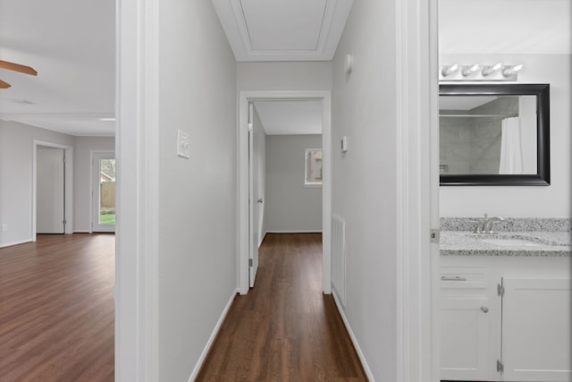 hallway featuring baseboards, dark wood-style floors, visible vents, and a sink