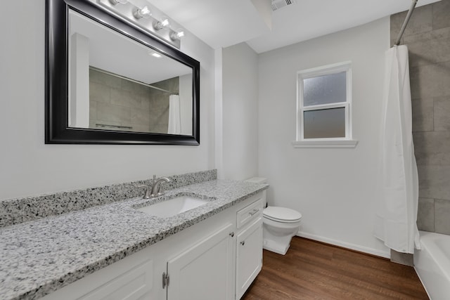 bathroom featuring vanity, wood finished floors, baseboards, shower / bath combo with shower curtain, and toilet