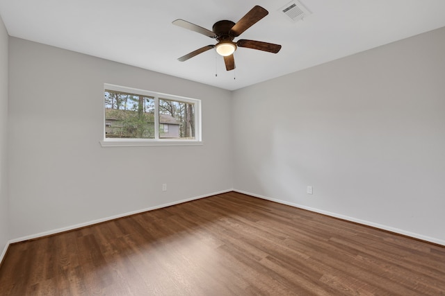 empty room featuring ceiling fan, visible vents, baseboards, and wood finished floors