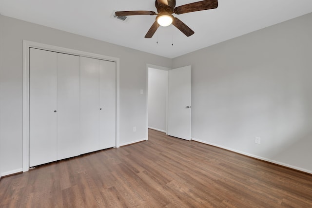 unfurnished bedroom featuring visible vents, wood finished floors, a closet, baseboards, and ceiling fan