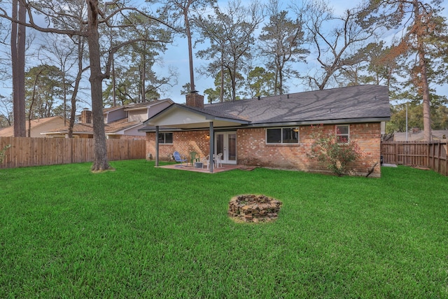 back of house with a lawn, a patio, a fenced backyard, french doors, and brick siding