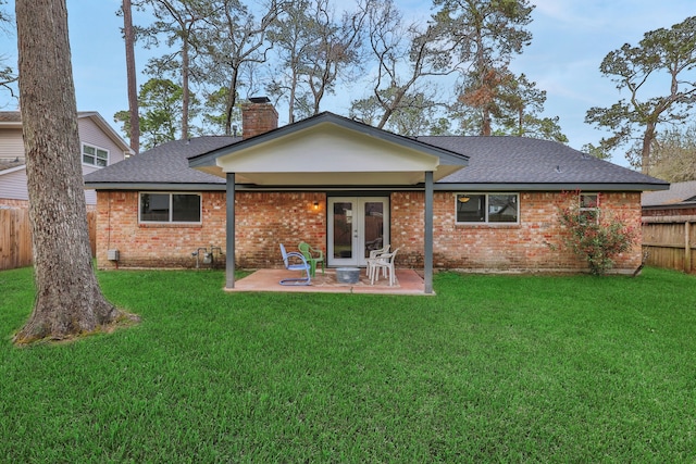 back of house with brick siding, fence, a lawn, french doors, and a patio area