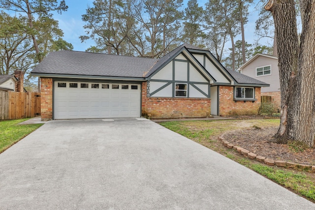 english style home with brick siding, an attached garage, a shingled roof, fence, and driveway