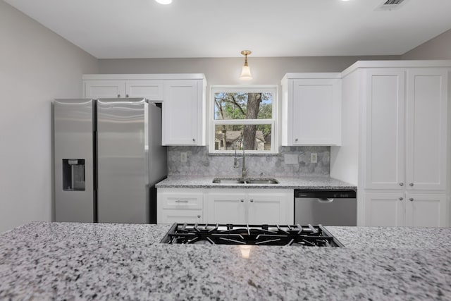 kitchen featuring backsplash, appliances with stainless steel finishes, white cabinets, and a sink