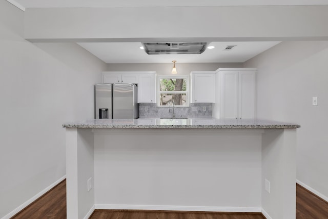 kitchen with visible vents, stainless steel refrigerator with ice dispenser, backsplash, white cabinetry, and baseboards