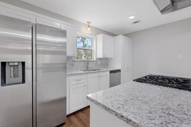 kitchen featuring dark wood-type flooring, decorative backsplash, stainless steel appliances, white cabinetry, and a sink