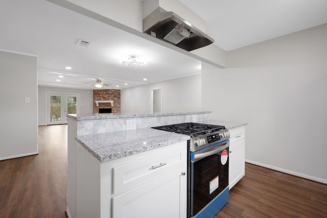 kitchen with light stone counters, visible vents, a fireplace, stainless steel range with gas stovetop, and dark wood-style flooring