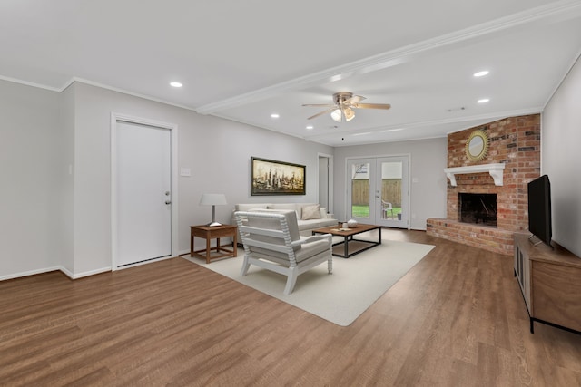 living area with recessed lighting, a brick fireplace, french doors, and wood finished floors